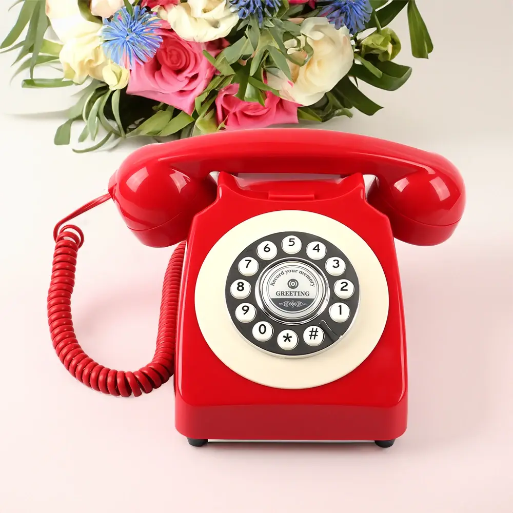 Telefon roșu cu tastatură albă și un buchet de flori deasupra