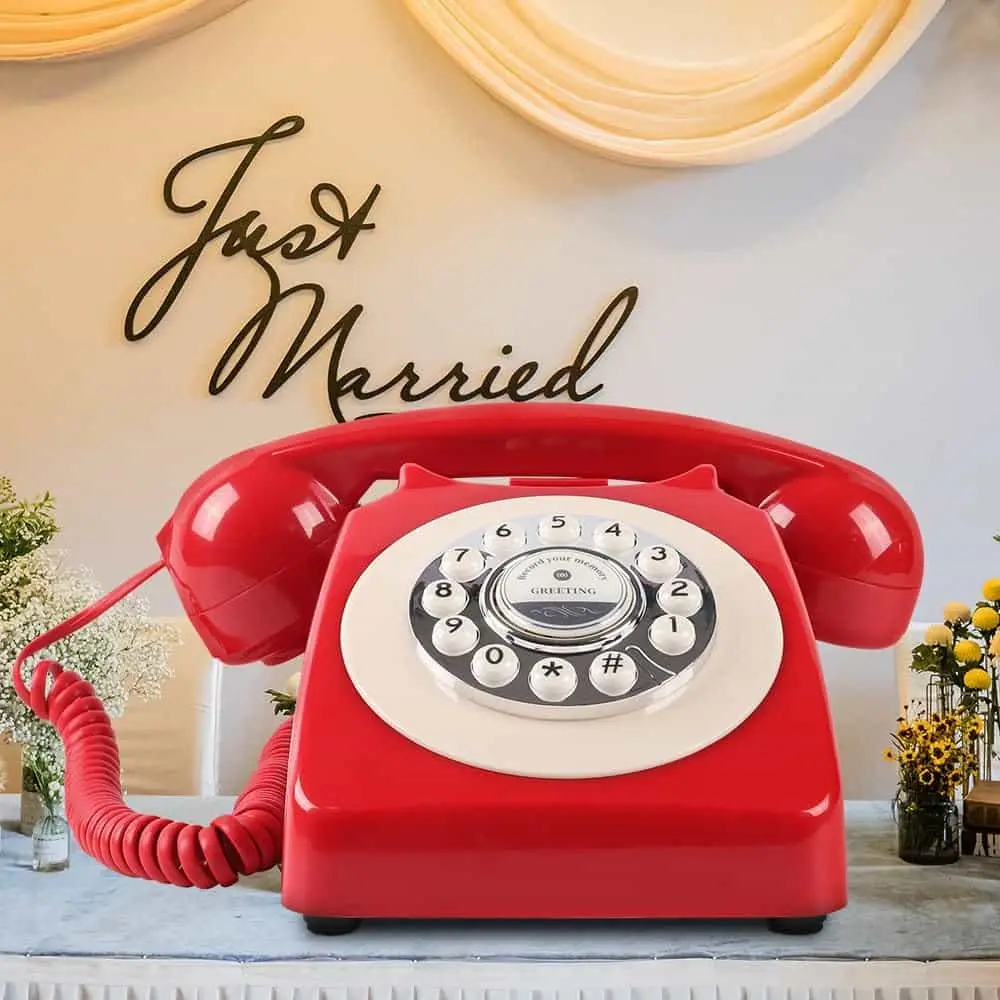 Telefon roșu pe o masă, cu inscripția Just Married pe perete în spate