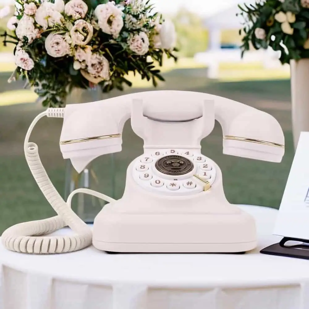 Telefon retro alb Elegance70 White pe o masă în aer liber, lângă flori