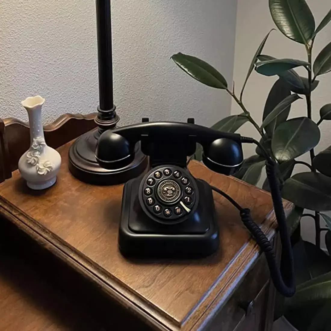 Telefon retro negru Elegance70 Black pe o comodă din lemn, lângă o lampă