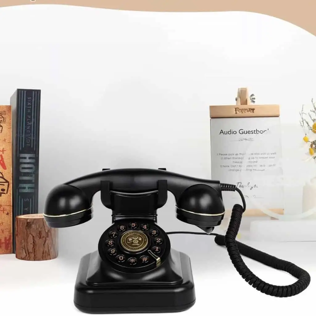 Telefon retro negru Elegance70 Black lângă cărți și un panou cu instrucțiuni