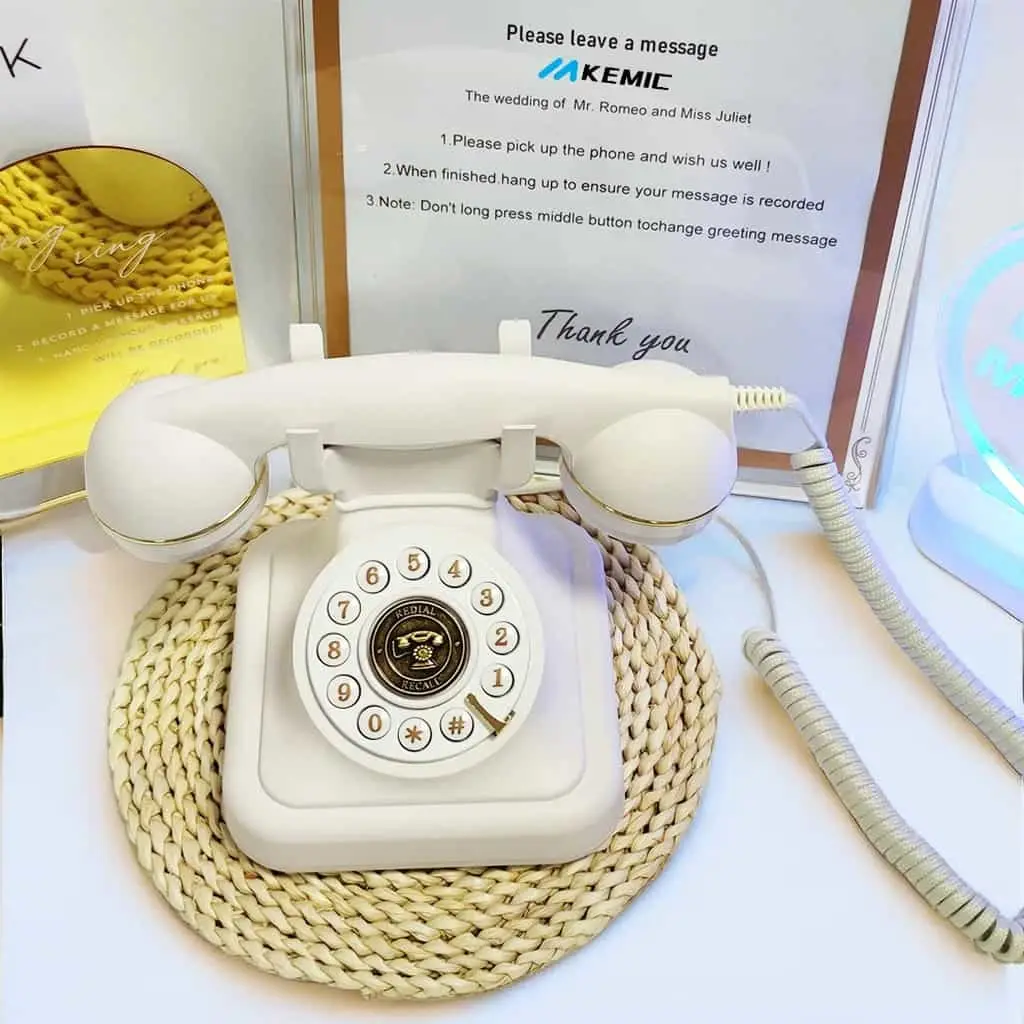 Telefon alb pe un suport împletit, în fața unui panou cu instrucțiuni pentru invitați